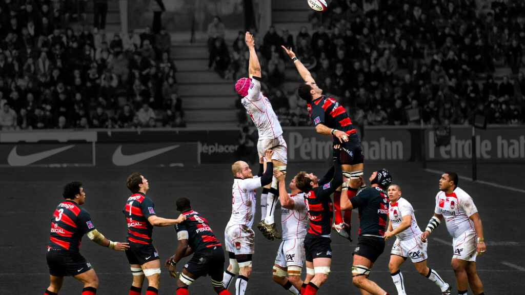 Jogadores de rugby no ar durante um salto no alinhamento lateral, mostrando as demandas físicas e o significado tático dos alinhamentos laterais.