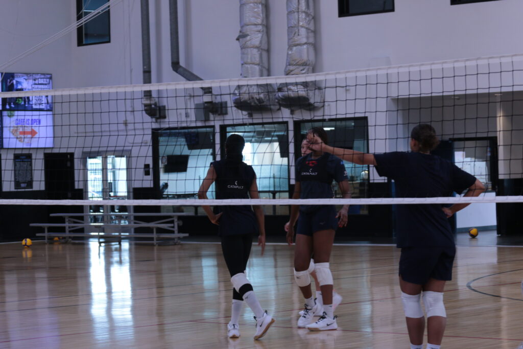 Joueurs de volley-ball participant à une séance d'entraînement, en mettant l'accent sur le dispositif Catapult porté sur leur dos.