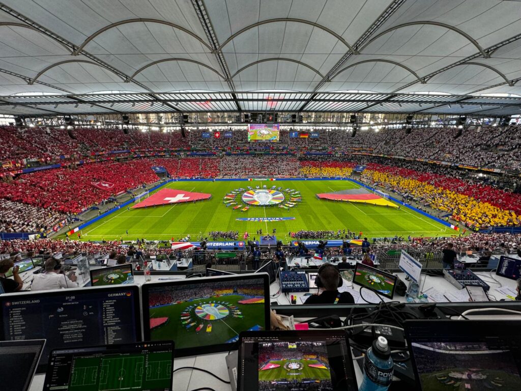 Vista aérea de un estadio repleto antes del partido Suiza vs Alemania, con computadoras portátiles configuradas para análisis en vivo.