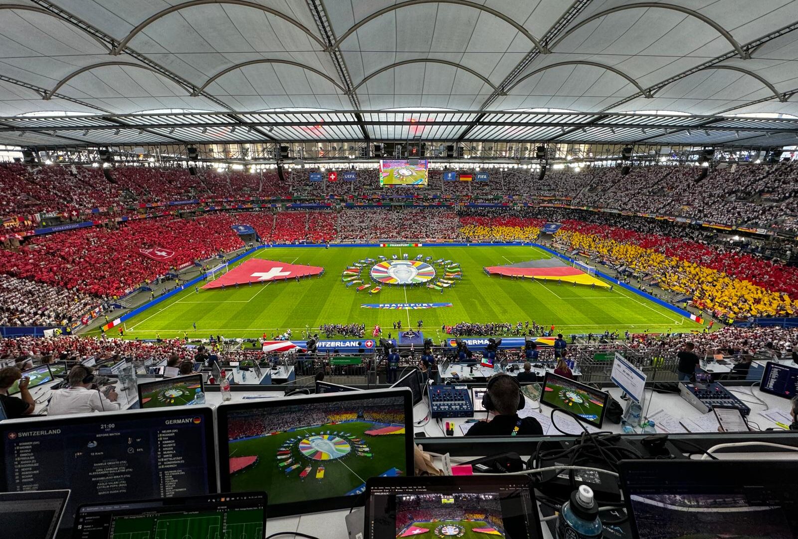 Aerial view of a packed stadium before the Switzerland vs Germany match, with laptops set up for live analysis.