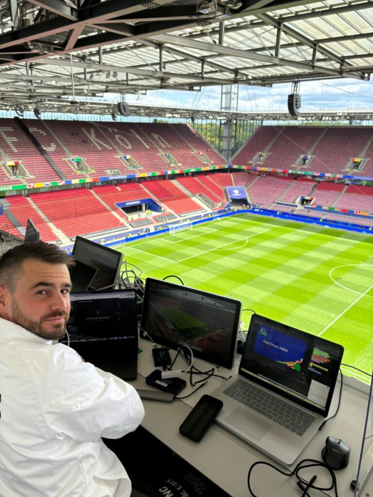 Nicolas Chappuis, analista da seleção sub-21 da Federação Suíça de Futebol, analisando dados de partidas em laptops em uma cabine do estádio.